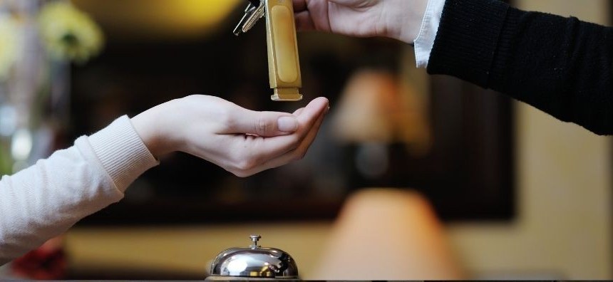 Hotel front-desk attendant handing a room key to a guest