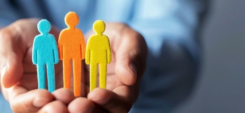 Hands holding three paper figures representing employees