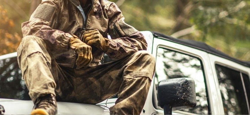 Hunting guide in field gear seated on a vehicle in the woods