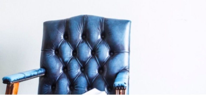 Blue tufted leather chair against a white wall