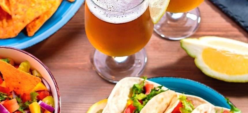 Restaurant table with tacos, salsa and craft beer
